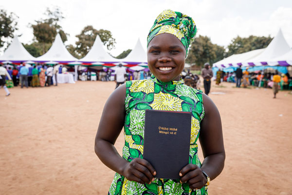 Smiling Ugandan woman displaying her new Bible